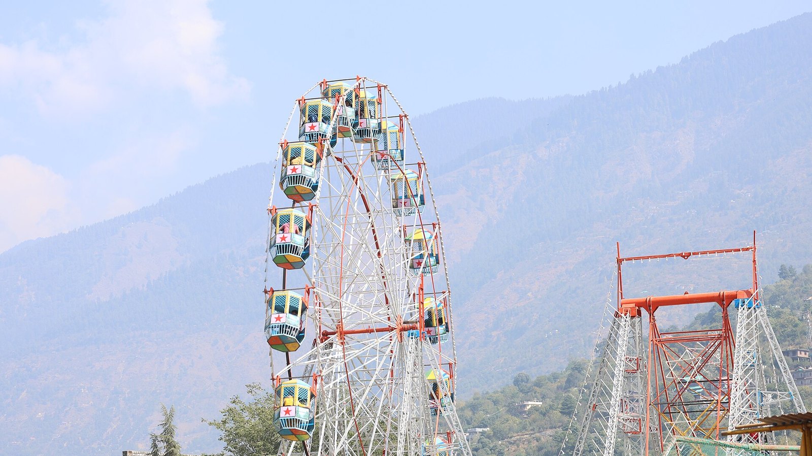 Giant wheel at the Kullu Dussehra fair with the valley hills behind