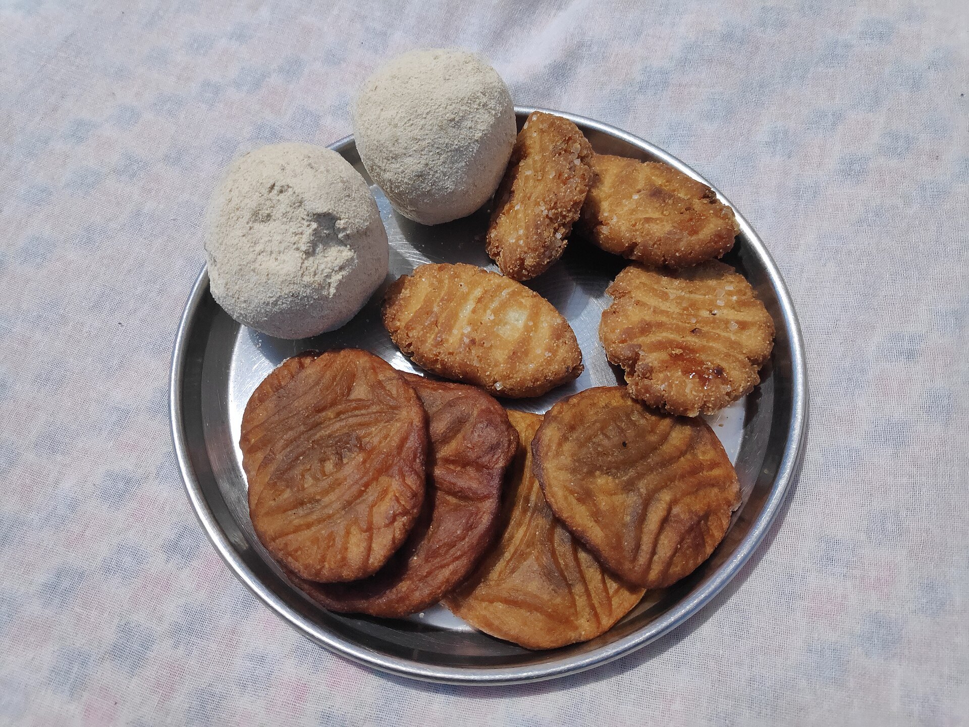 Thekua and laddu, the Chhath Puja prasad, on a steel plate
