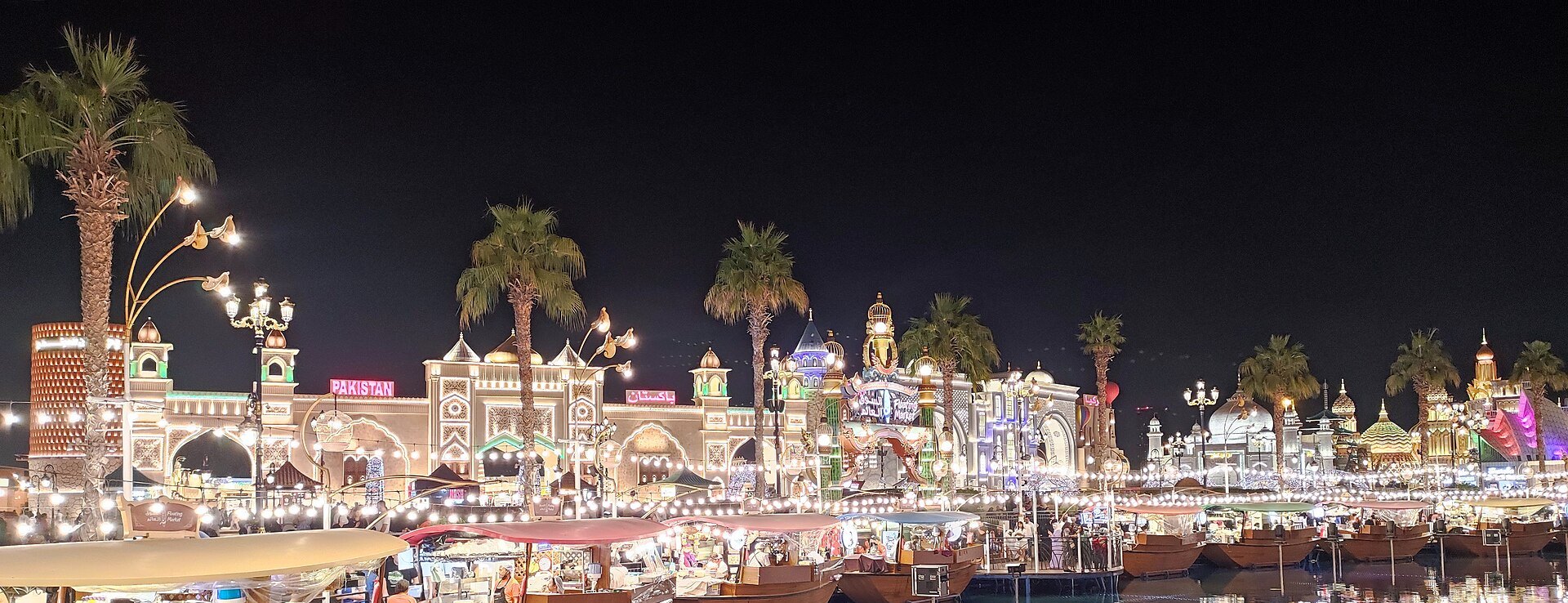 Global Village Dubai lit up at night with its canal and pavilions during the winter season