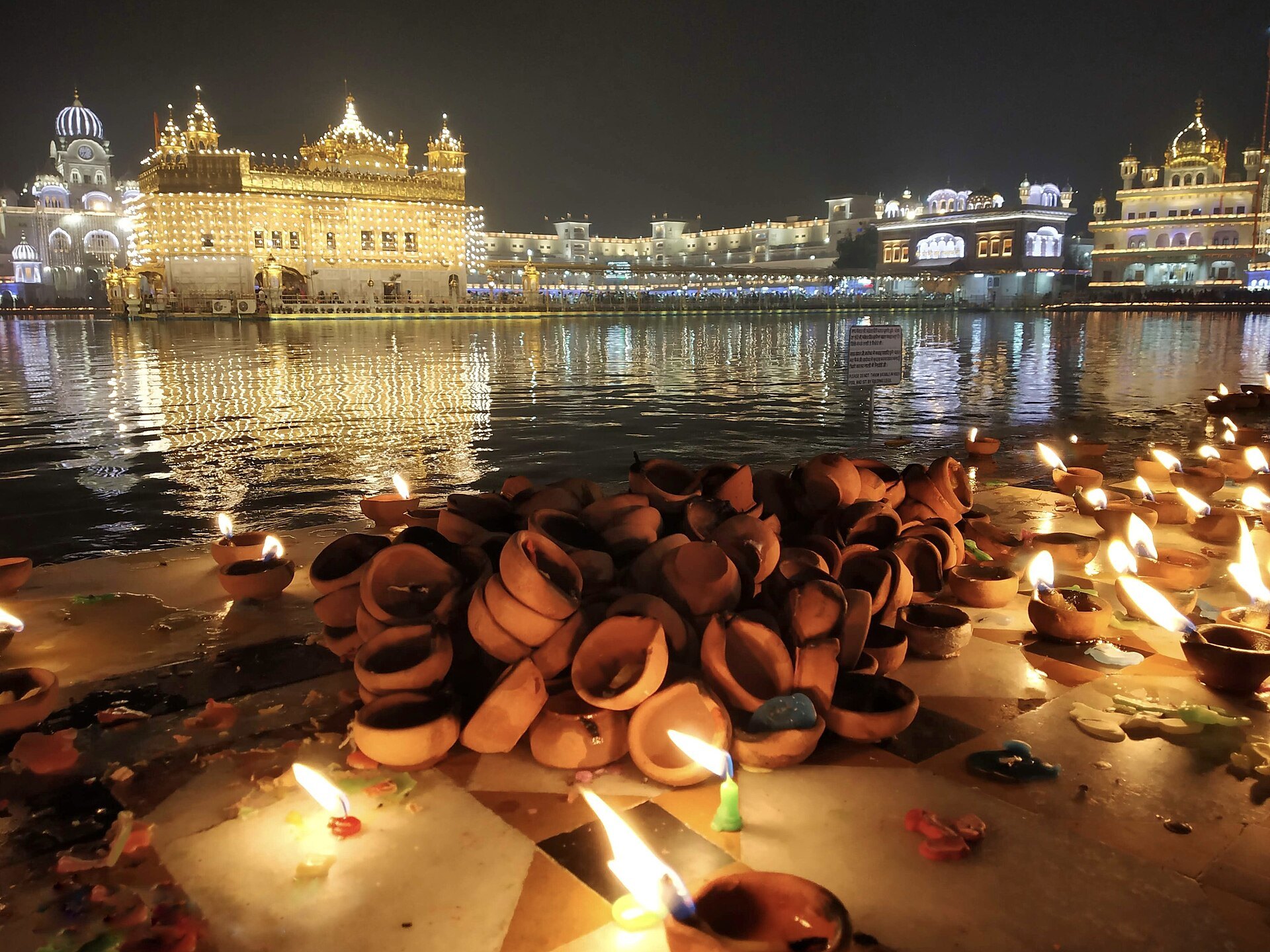 Diyas on the parikrama with the Golden Temple lit up for Bandi Chhor Divas and Diwali in Amritsar