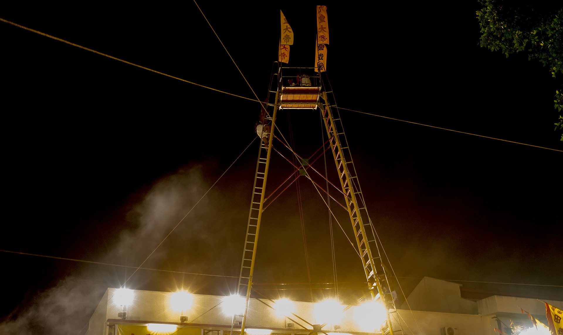Bladed ladder tower lit up at night outside a shrine during the Phuket Vegetarian Festival