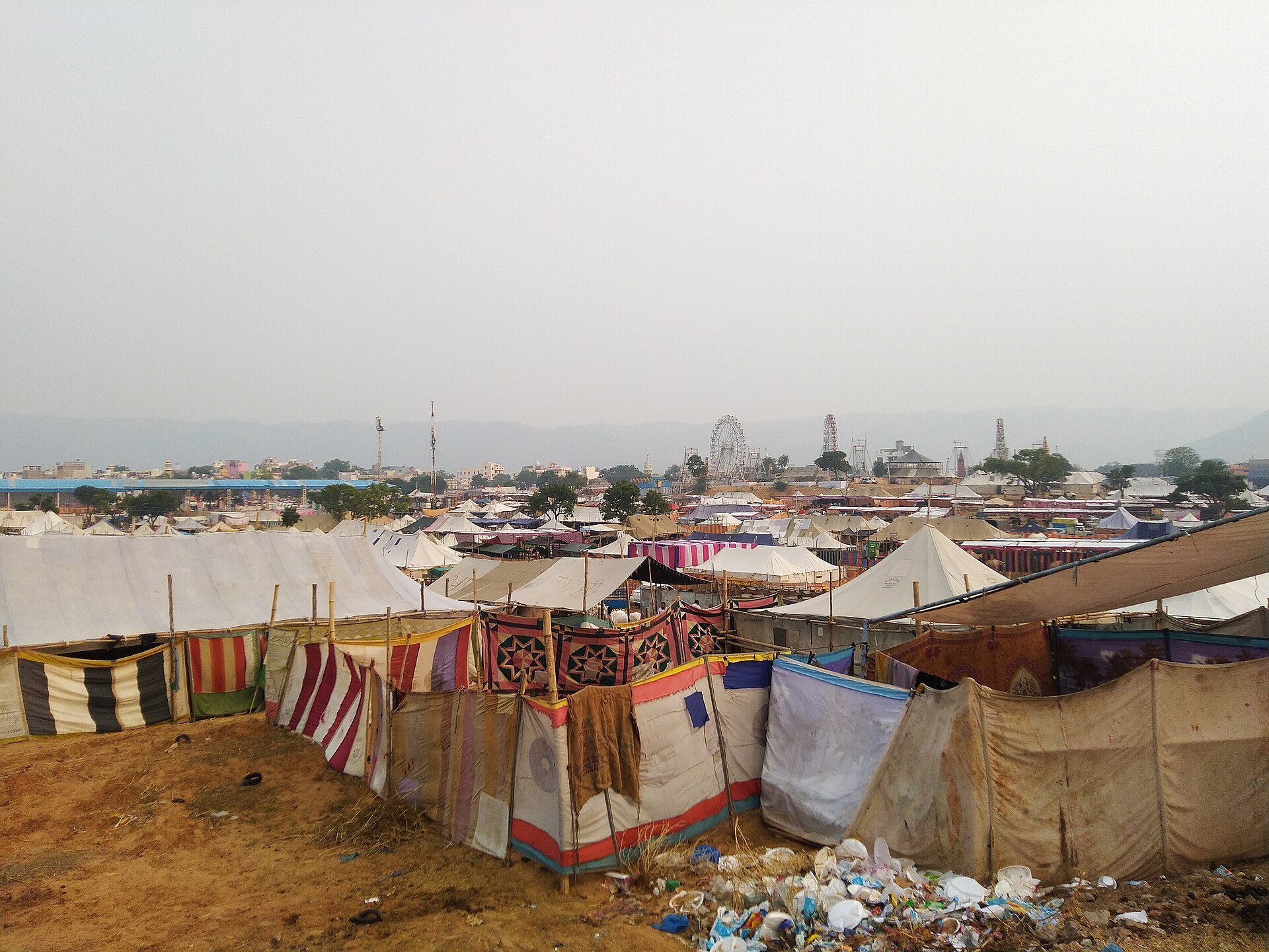 Traders' tents at Pushkar Mela with the ferris wheels of the fair ground in the background